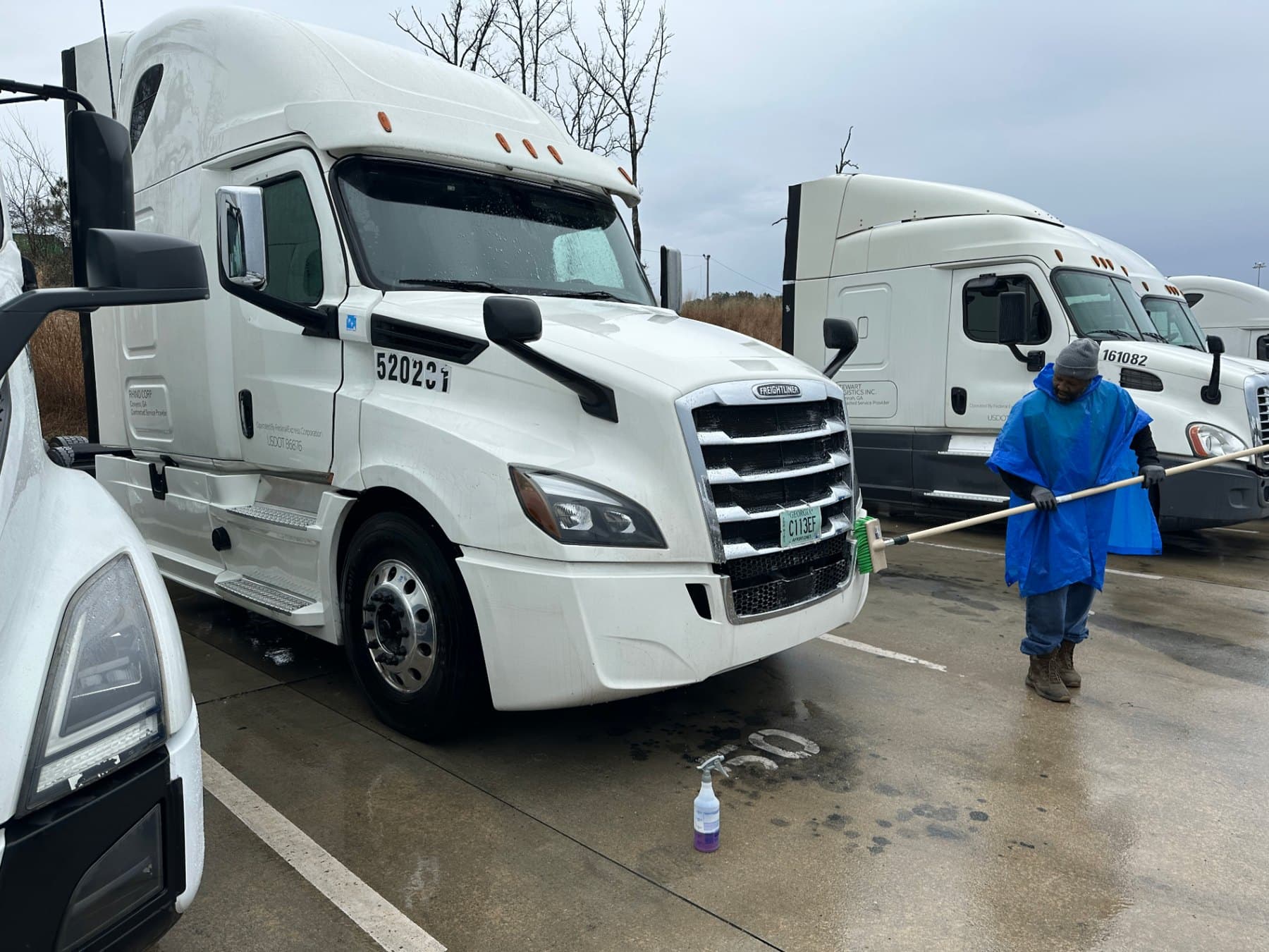 Buck A1 technician washing a white semi truck in a truck yard